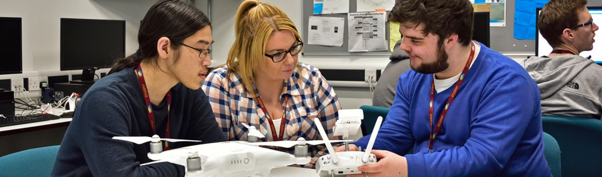 Three WMC Digital and Computing Technologies Intermediate students playing with drone in classroom