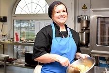 Wirral Met Hospitality and Catering student wearing a blue apron and stiring a mixing bowl